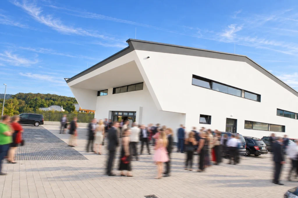 Eventhalle in Kelkheim mit markanter Dachform und Veranstaltungsgästen in Bewegungsunschärfe auf dem Vorplatz