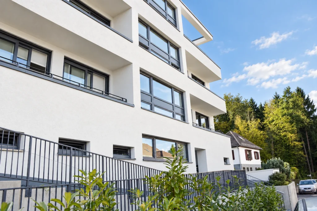Straßenfassade des Mehrfamilienhauses in Kelkheim mit anthrazitfarbenen Fensterrahmen und begrüntem Vorbereich