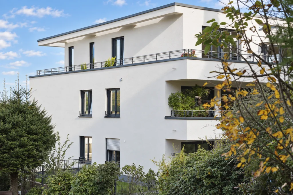 Seitenansicht des Mehrfamilienhauses in Kelkheim mit umlaufenden Balkonen und Gartenbepflanzung