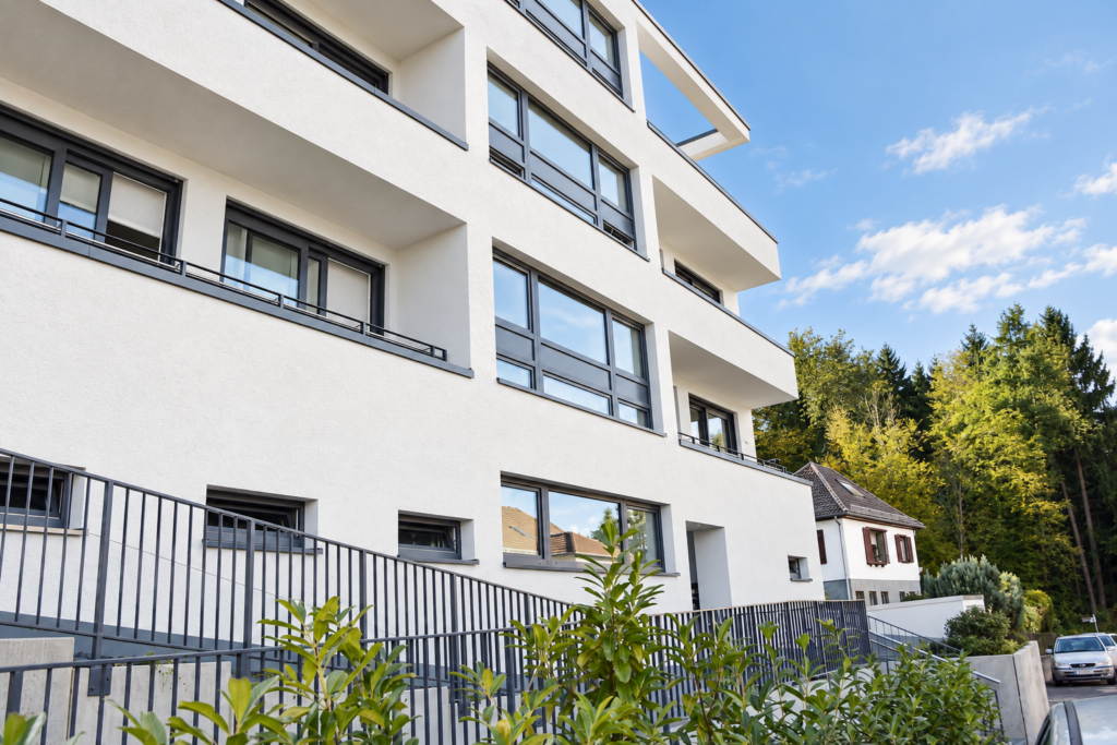 Straßenfassade des Mehrfamilienhauses in Kelkheim mit anthrazitfarbenen Fensterrahmen und begrüntem Vorbereich